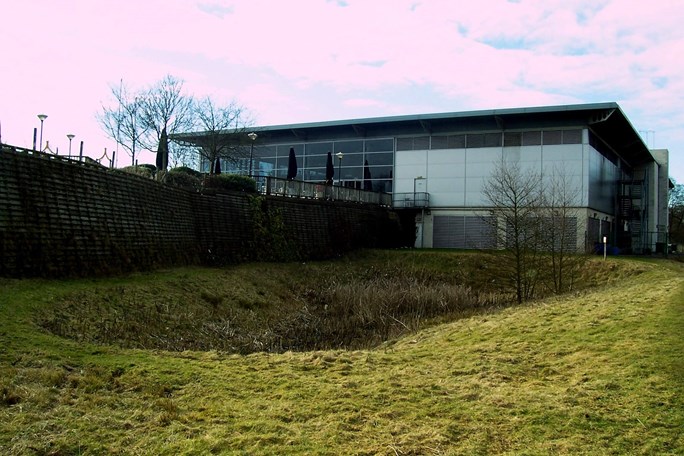 Grassy detention basin outside modern glass building