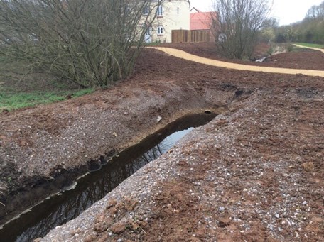 Excavated channel filled with water in newly built development. 