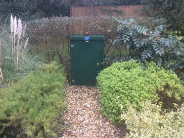 Kiosk for pumped drainage on a gravel path next to shrubs